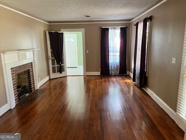 unfurnished living room with ornamental molding, a brick fireplace, a textured ceiling, and dark wood-type flooring