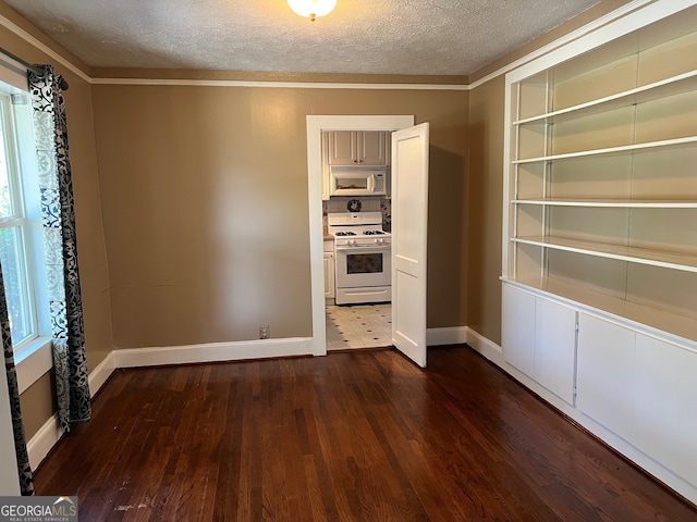 empty room featuring a textured ceiling, dark hardwood / wood-style floors, and crown molding