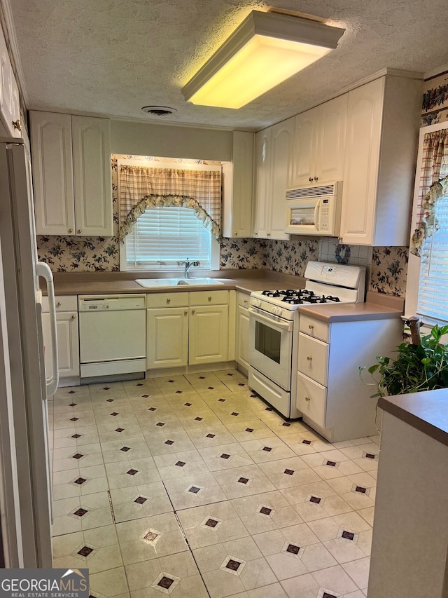 kitchen featuring white appliances, a textured ceiling, and sink