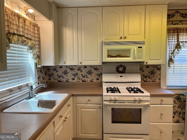 kitchen featuring white appliances, white cabinetry, and sink