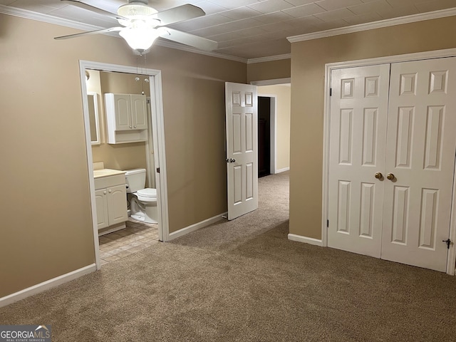 unfurnished bedroom featuring ceiling fan, crown molding, a closet, light carpet, and ensuite bath