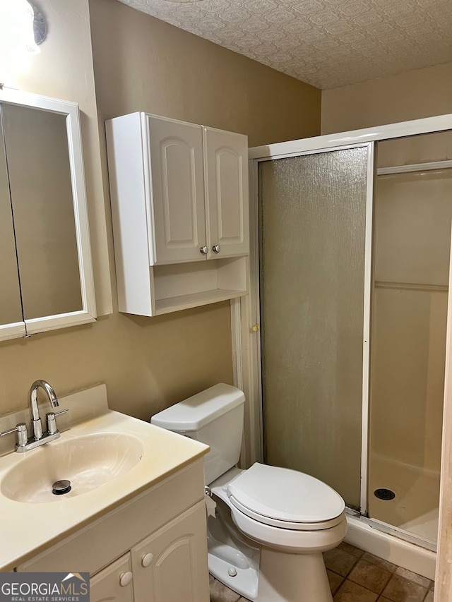 bathroom with a textured ceiling, tile patterned floors, a shower with shower door, vanity, and toilet