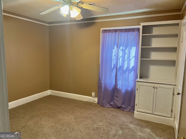 carpeted empty room with ceiling fan, crown molding, and a textured ceiling