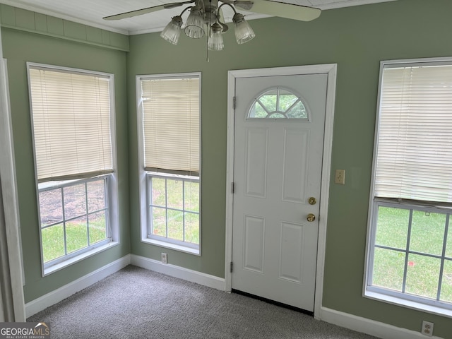 foyer entrance with ceiling fan, carpet flooring, and a wealth of natural light