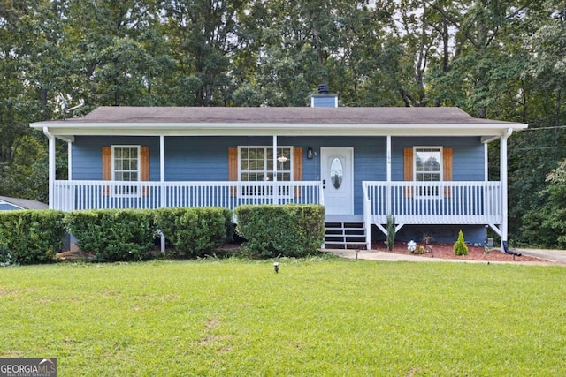 view of front of home with covered porch, a chimney, and a front yard