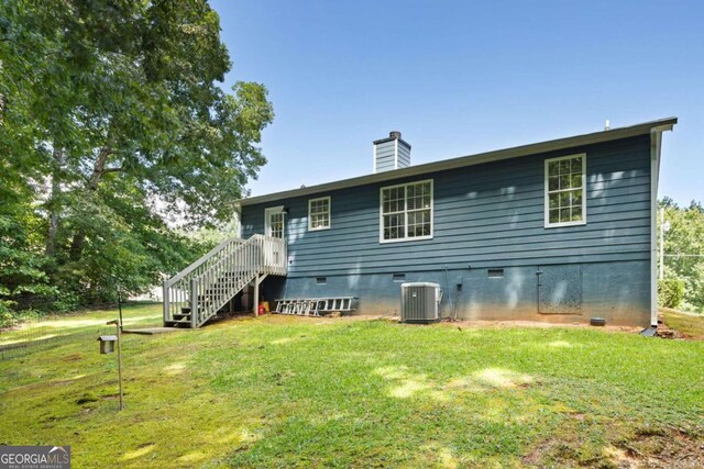 back of property featuring a yard and central AC