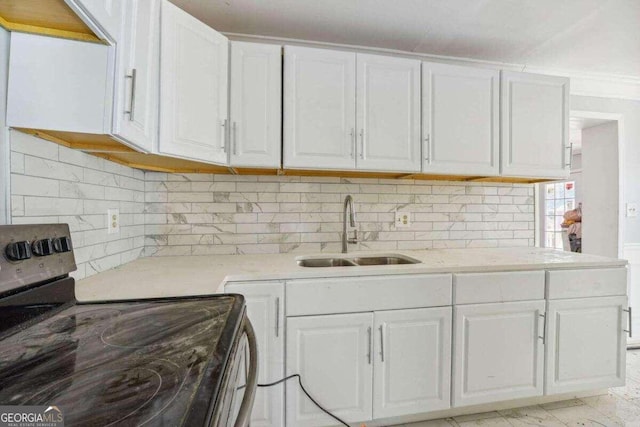 kitchen with light tile patterned flooring, backsplash, sink, stainless steel range with electric stovetop, and white cabinets