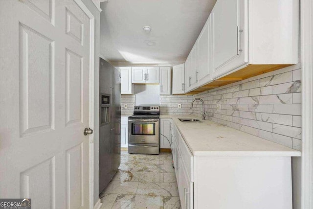 kitchen with tasteful backsplash, white cabinets, appliances with stainless steel finishes, light tile patterned floors, and sink