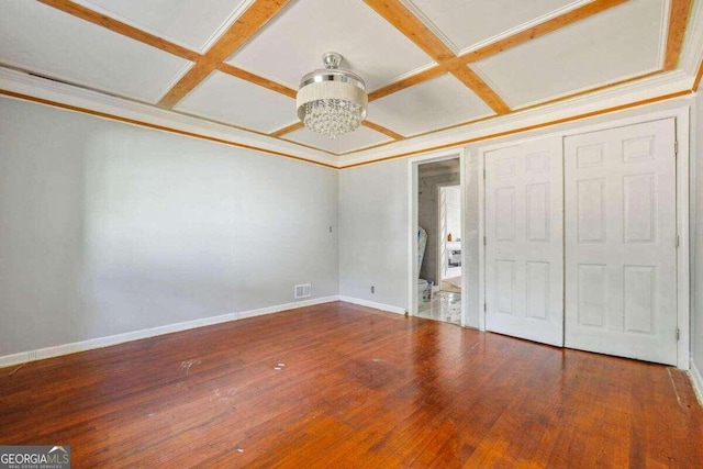 unfurnished bedroom featuring a closet, a chandelier, hardwood / wood-style flooring, and coffered ceiling