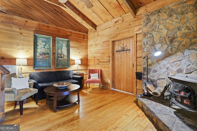 interior space featuring light wood-type flooring, lofted ceiling with beams, a wood stove, and wood walls