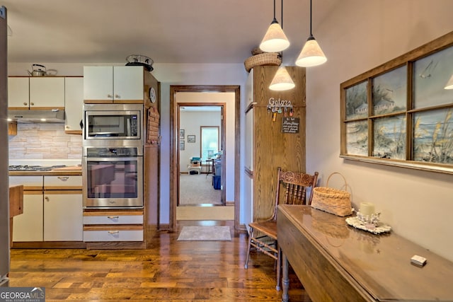 kitchen featuring dark hardwood / wood-style flooring, stainless steel appliances, backsplash, and pendant lighting