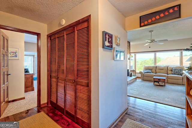 corridor with a textured ceiling and hardwood / wood-style floors