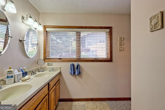 bathroom with vanity, a textured ceiling, and a healthy amount of sunlight