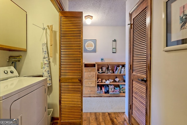 washroom with dark wood-type flooring, washer and dryer, a textured ceiling, and cabinets