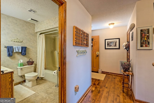 full bathroom with hardwood / wood-style floors, a textured ceiling, toilet, shower / bath combo, and vanity