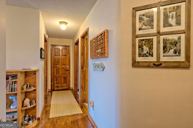 hall with a textured ceiling and wood-type flooring