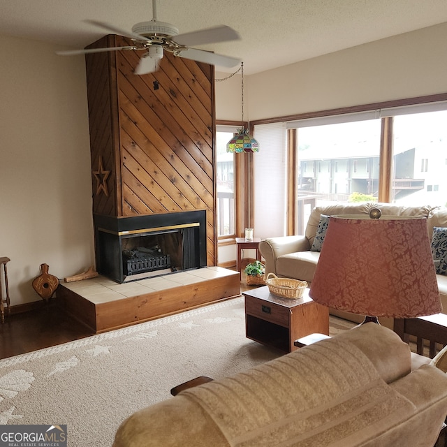 living room featuring a large fireplace, a textured ceiling, a healthy amount of sunlight, and ceiling fan