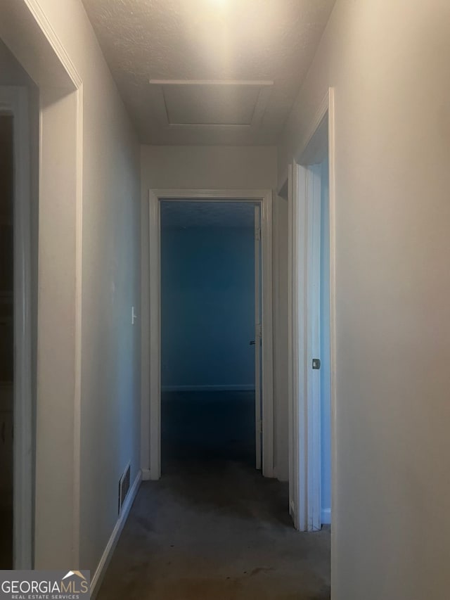 hallway with a textured ceiling and concrete flooring