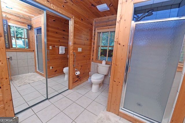 bathroom with wooden walls, tile patterned flooring, a shower with door, and toilet