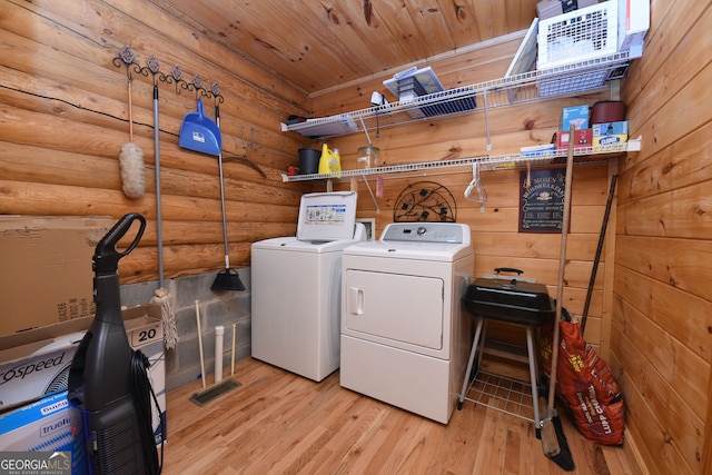 clothes washing area featuring washer and clothes dryer, rustic walls, light hardwood / wood-style floors, and wooden ceiling