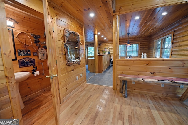 interior space featuring hardwood / wood-style flooring, wood ceiling, and log walls