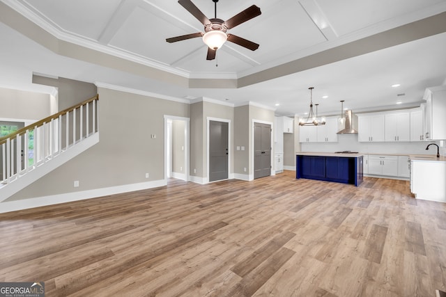 unfurnished living room featuring ceiling fan with notable chandelier, crown molding, sink, and light hardwood / wood-style floors