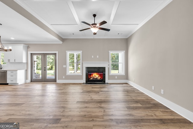 unfurnished living room with ceiling fan with notable chandelier, crown molding, and wood-type flooring