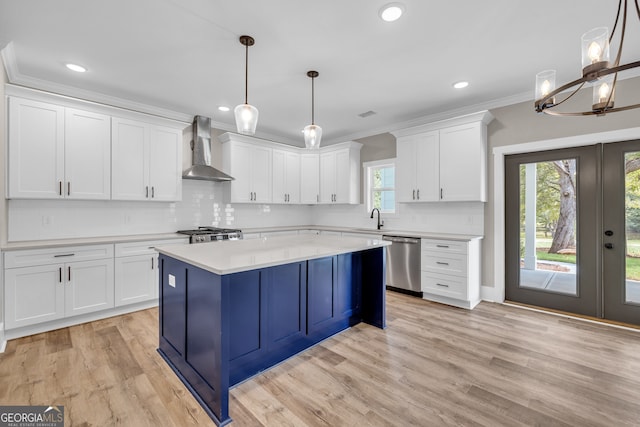 kitchen featuring appliances with stainless steel finishes, a wealth of natural light, decorative light fixtures, and wall chimney range hood