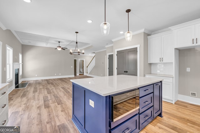 kitchen with light hardwood / wood-style flooring, blue cabinetry, hanging light fixtures, ornamental molding, and white cabinets