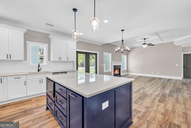 kitchen with white cabinets, blue cabinets, sink, and a healthy amount of sunlight