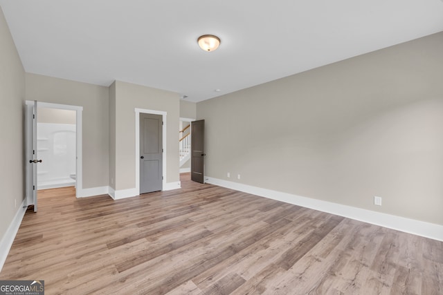 unfurnished bedroom featuring light wood-type flooring and ensuite bathroom