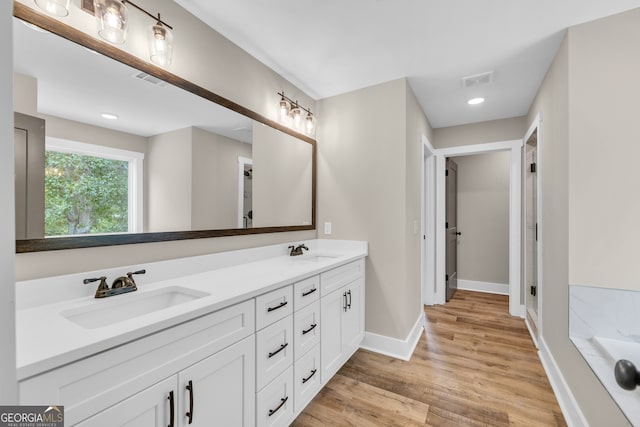 bathroom featuring hardwood / wood-style floors, a washtub, and vanity