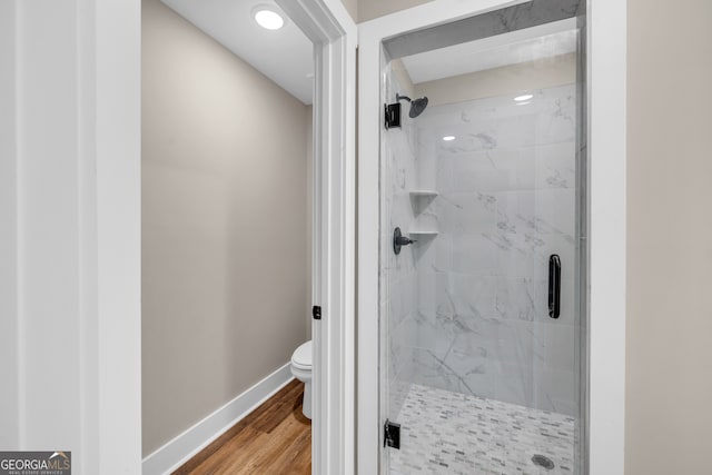 bathroom with an enclosed shower, toilet, and hardwood / wood-style flooring