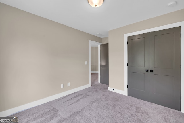 unfurnished bedroom with a closet and light colored carpet