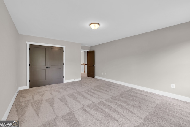 unfurnished bedroom with a closet and light colored carpet