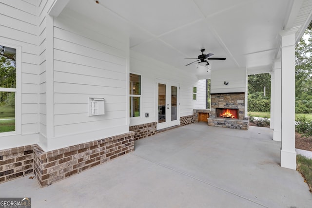 view of patio with an outdoor stone fireplace, ceiling fan, and french doors