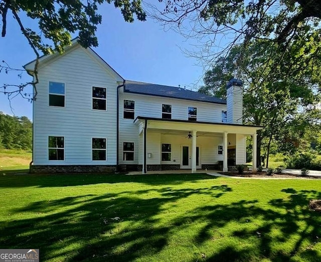 rear view of house featuring ceiling fan and a lawn