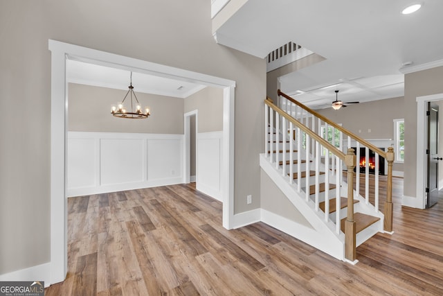 interior space with crown molding, ceiling fan with notable chandelier, and hardwood / wood-style flooring