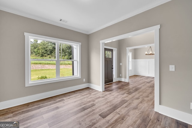 unfurnished room with wood-type flooring, an inviting chandelier, and ornamental molding