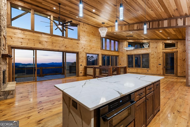 kitchen featuring a spacious island, wood ceiling, light stone counters, and hanging light fixtures