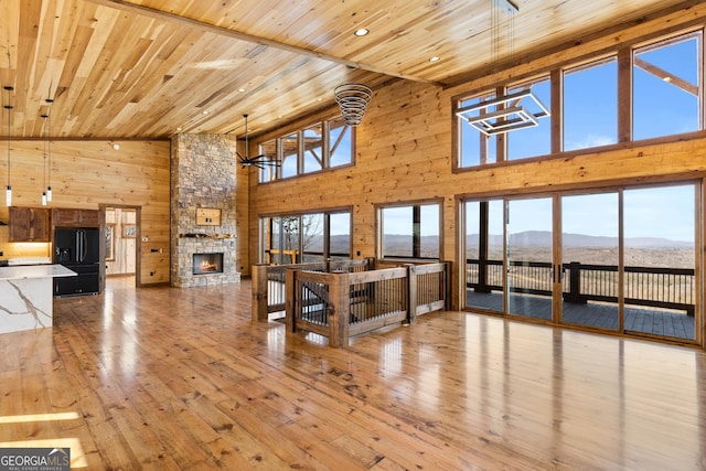 unfurnished living room featuring a mountain view, wooden ceiling, wooden walls, and a fireplace