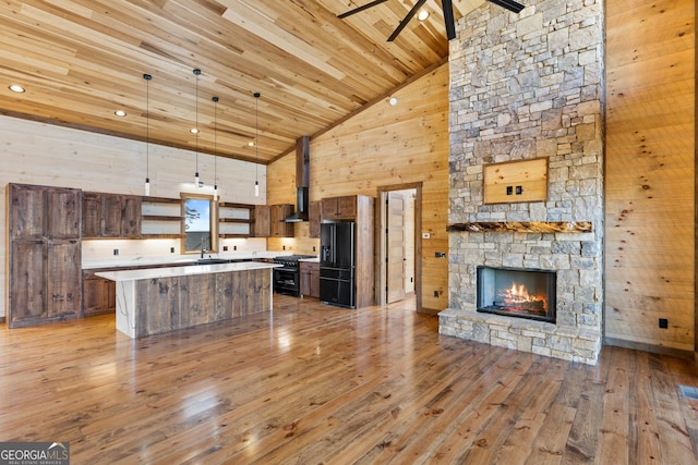 kitchen with range with gas cooktop, decorative light fixtures, a center island, wood ceiling, and black fridge