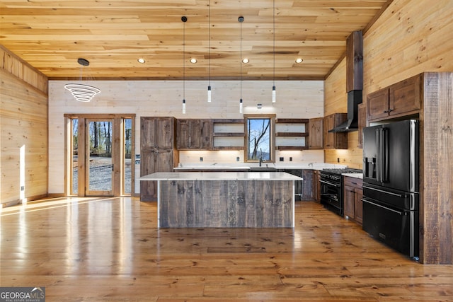 kitchen featuring high end appliances, wood ceiling, hanging light fixtures, a kitchen island, and wall chimney range hood