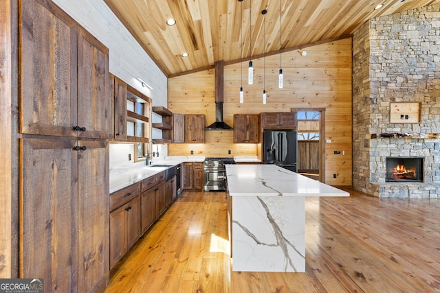 kitchen featuring black fridge, a center island, light hardwood / wood-style flooring, wooden ceiling, and high end stainless steel range oven