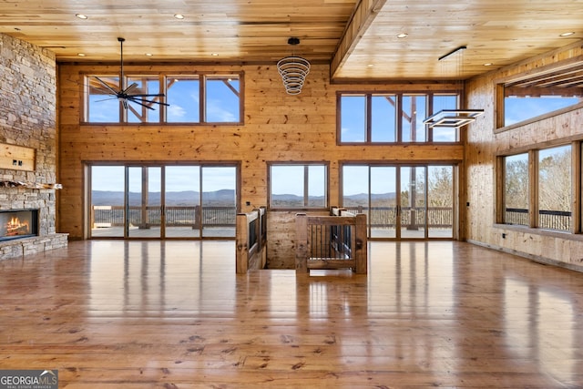 living room featuring wood-type flooring, wooden ceiling, a mountain view, a towering ceiling, and a fireplace