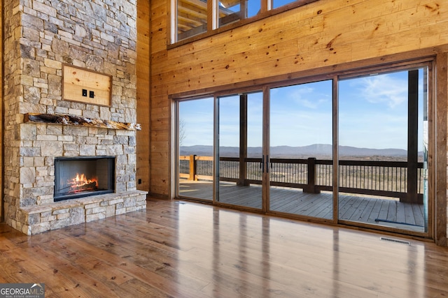 unfurnished living room with a healthy amount of sunlight, a stone fireplace, a mountain view, and hardwood / wood-style floors