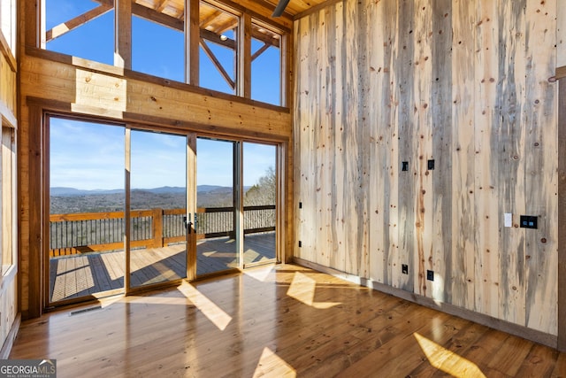 unfurnished room with a mountain view, a high ceiling, and light wood-type flooring