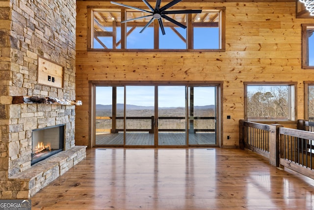 unfurnished living room with wood-type flooring, a mountain view, a fireplace, and wooden walls