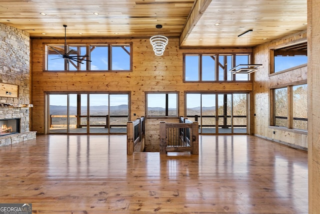 living room featuring a stone fireplace, wood ceiling, wood-type flooring, a mountain view, and a towering ceiling