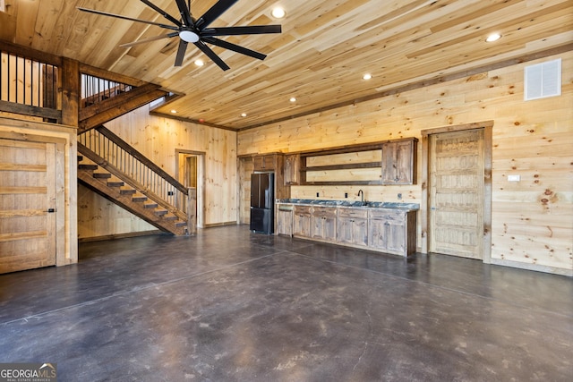 unfurnished living room with wood ceiling, ceiling fan, wet bar, and wood walls